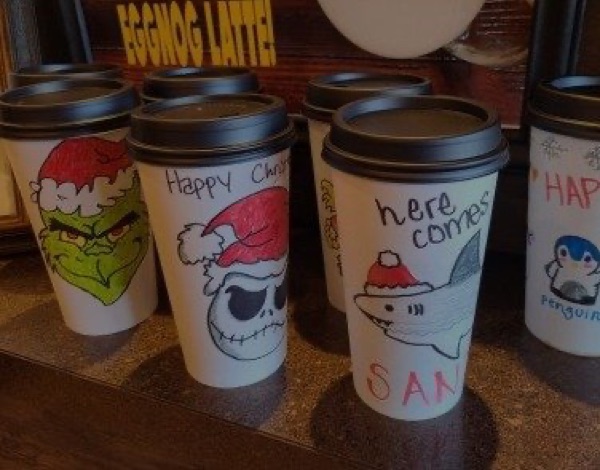 Hand-decorated holiday coffee cups lined up on the counter